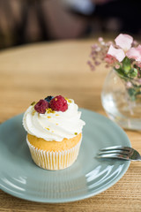 Cupcake with white cream and berries on the table