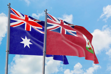 Fototapeta premium Bermuda and Australia flags waving in the wind against white cloudy blue sky together. Diplomacy concept, international relations.