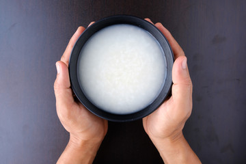 Hand holding bowl of mush rice