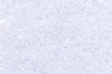 Close-up snow texture. Bright white and shades of blue. Blank, textured snow surface.