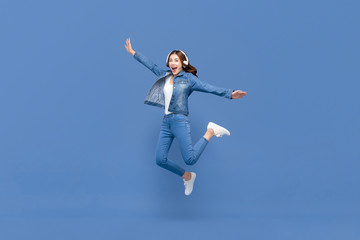 Fototapeta na wymiar Asian woman jumping while listening to music on headphones