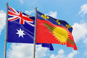 Guadeloupe and Australia flags waving in the wind against white cloudy blue sky together. Diplomacy concept, international relations.
