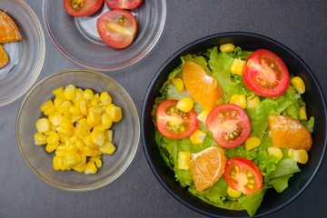 Salad of lettuce and  cherry tomato,orange,corn in bowl.Concept for a tasty and healthy meal.vegetarian food healthy concept.topview