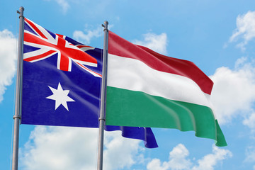 Hungary and Australia flags waving in the wind against white cloudy blue sky together. Diplomacy concept, international relations.
