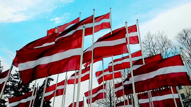 Latvian flags attached to a pole waving in the wind, the skyline of Riga, Latvia, concept of travel