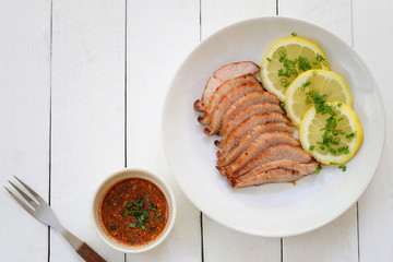 Grilled Pork and Lemon Slice in white dish on white wooden floor and have copy space.