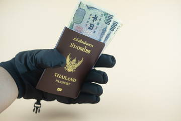 Hand of a man in a winter glove holding Thailand passport ann Yen money