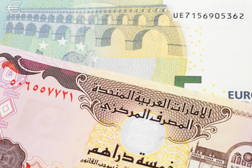 A blue and green, European five euro bank note with a five dirham bank note from the United Arab Emirates close up in macro