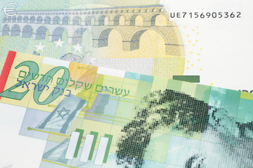 A twenty shekel note from Israel close up in macro with a blue and green, European five euro bank note