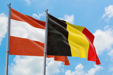 Belgium and Austria flags waving in the wind against white cloudy blue sky together. Diplomacy concept, international relations.