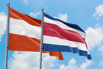 Fototapeta na wymiar Costa Rica and Austria flags waving in the wind against white cloudy blue sky together. Diplomacy concept, international relations.