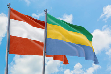 Gabon and Austria flags waving in the wind against white cloudy blue sky together. Diplomacy concept, international relations.