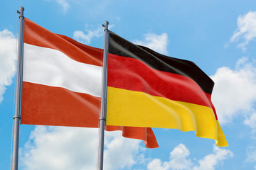 Germany and Austria flags waving in the wind against white cloudy blue sky together. Diplomacy concept, international relations.