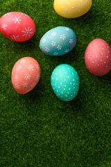 Fototapeta na wymiar Easter greetings. Easter painted eggs on green grass. Easter religious holiday Easter. Vertical frame with space.