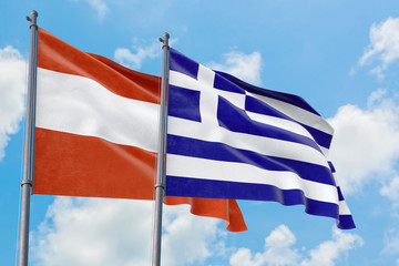 Greece and Austria flags waving in the wind against white cloudy blue sky together. Diplomacy concept, international relations.