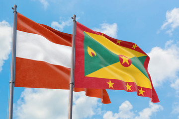 Grenada and Austria flags waving in the wind against white cloudy blue sky together. Diplomacy concept, international relations.