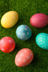 Easter eggs colored on green grass. Congratulations on Easter. Vertical frame.