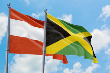Jamaica and Austria flags waving in the wind against white cloudy blue sky together. Diplomacy concept, international relations.