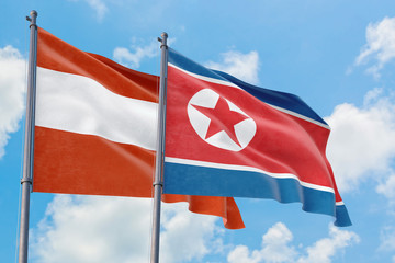 North Korea and Austria flags waving in the wind against white cloudy blue sky together. Diplomacy concept, international relations.