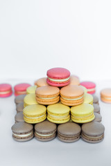Close up of tray with lot delicious diversity pastry cakes tartlets and macaroon in a row. Fresh, multicoloured, colourful, green, yellow, white and pink sweet berry desserts, beautifully decorated