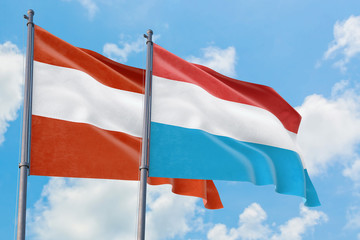 Luxembourg and Austria flags waving in the wind against white cloudy blue sky together. Diplomacy concept, international relations.