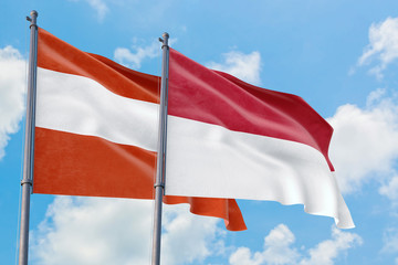 Monaco and Austria flags waving in the wind against white cloudy blue sky together. Diplomacy concept, international relations.