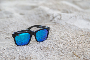 Fototapeta na wymiar Blue sunglasses on white sand