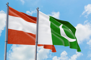 Pakistan and Austria flags waving in the wind against white cloudy blue sky together. Diplomacy concept, international relations.