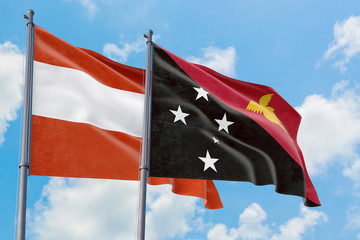Papua New Guinea and Austria flags waving in the wind against white cloudy blue sky together. Diplomacy concept, international relations.