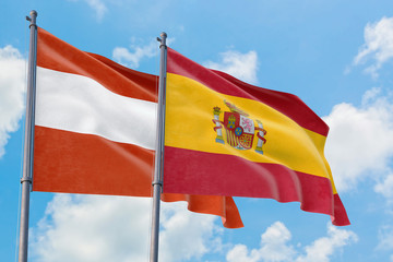 Spain and Austria flags waving in the wind against white cloudy blue sky together. Diplomacy concept, international relations.