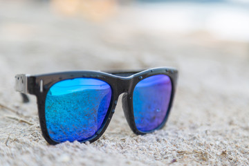 Blue sunglasses on white sand