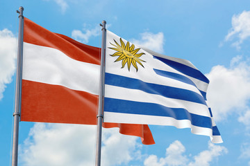 Uruguay and Austria flags waving in the wind against white cloudy blue sky together. Diplomacy concept, international relations.