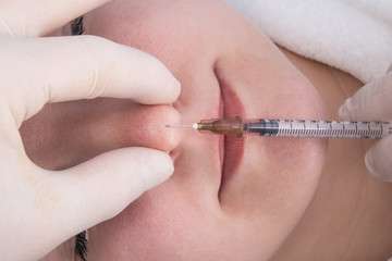 a woman is injected into the tip of the nose to correct the shape of the face, top view