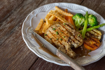 Black pepper pork chop in white plate on wooden table