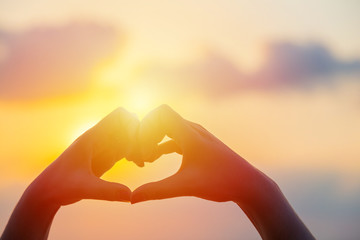 Hands make in heart form love with silhouette at sun set
