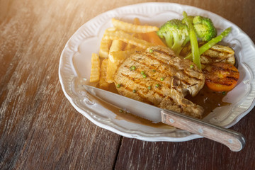 Black pepper pork chop in white plate on wooden table