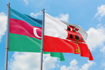 Gibraltar and Azerbaijan flags waving in the wind against white cloudy blue sky together. Diplomacy concept, international relations.