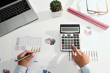 businesswoman working on desk using calculator and laptop analyzing finance accounting in office