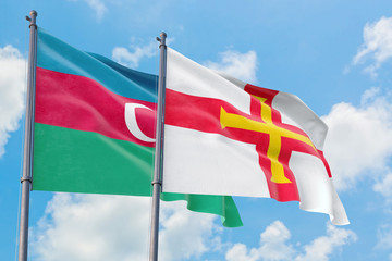 Guernsey and Azerbaijan flags waving in the wind against white cloudy blue sky together. Diplomacy concept, international relations.