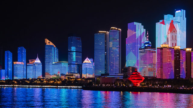 Scenic night view from the Urban park new town seaside of Qingdao, China.Seaside tourist town that is popular with Chinese people.Building lighting show With beautiful color lights at night. © bunditinay