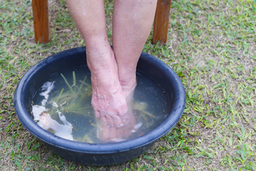 Close-up of spa foot with herbs water for relaxation treatment. Senior woman have a ankle pain use herbal treatment to relax the muscles by soaking warm water that is boiled from herbs