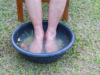 Close-up of spa foot with herbs water for relaxation treatment. Senior woman have a ankle pain use herbal treatment to relax the muscles by soaking warm water that is boiled from herbs