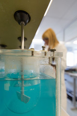 Chemical mixing in tank with female worker at laboratory