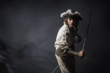 medieval bearded pirate with a sword and gun. concept photo of handsome man in a pirate vintage...