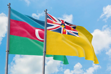 Niue and Azerbaijan flags waving in the wind against white cloudy blue sky together. Diplomacy concept, international relations.