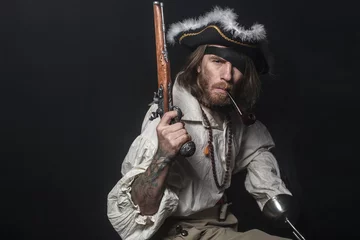 Fotobehang medieval bearded pirate with a sword and gun. concept photo of handsome man in a pirate vintage costume with pistol and saber © Fotokvadrat