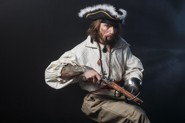 Fototapeta premium średniowieczny brodaty pirat z mieczem i pistoletem. koncepcja zdjęcie przystojny mężczyzna w pirackim kostiumie vintage z pistoletem i szablą