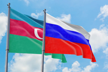 Russia and Azerbaijan flags waving in the wind against white cloudy blue sky together. Diplomacy concept, international relations.