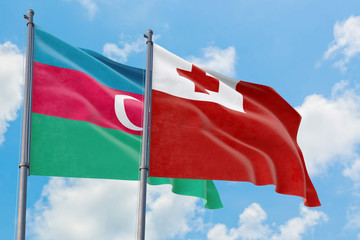 Tonga and Azerbaijan flags waving in the wind against white cloudy blue sky together. Diplomacy concept, international relations.