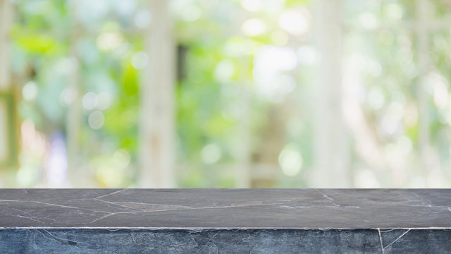 Empty black marble stone table top and blurred of interior room with window view from green tree garden background background - can used for display or montage your products.